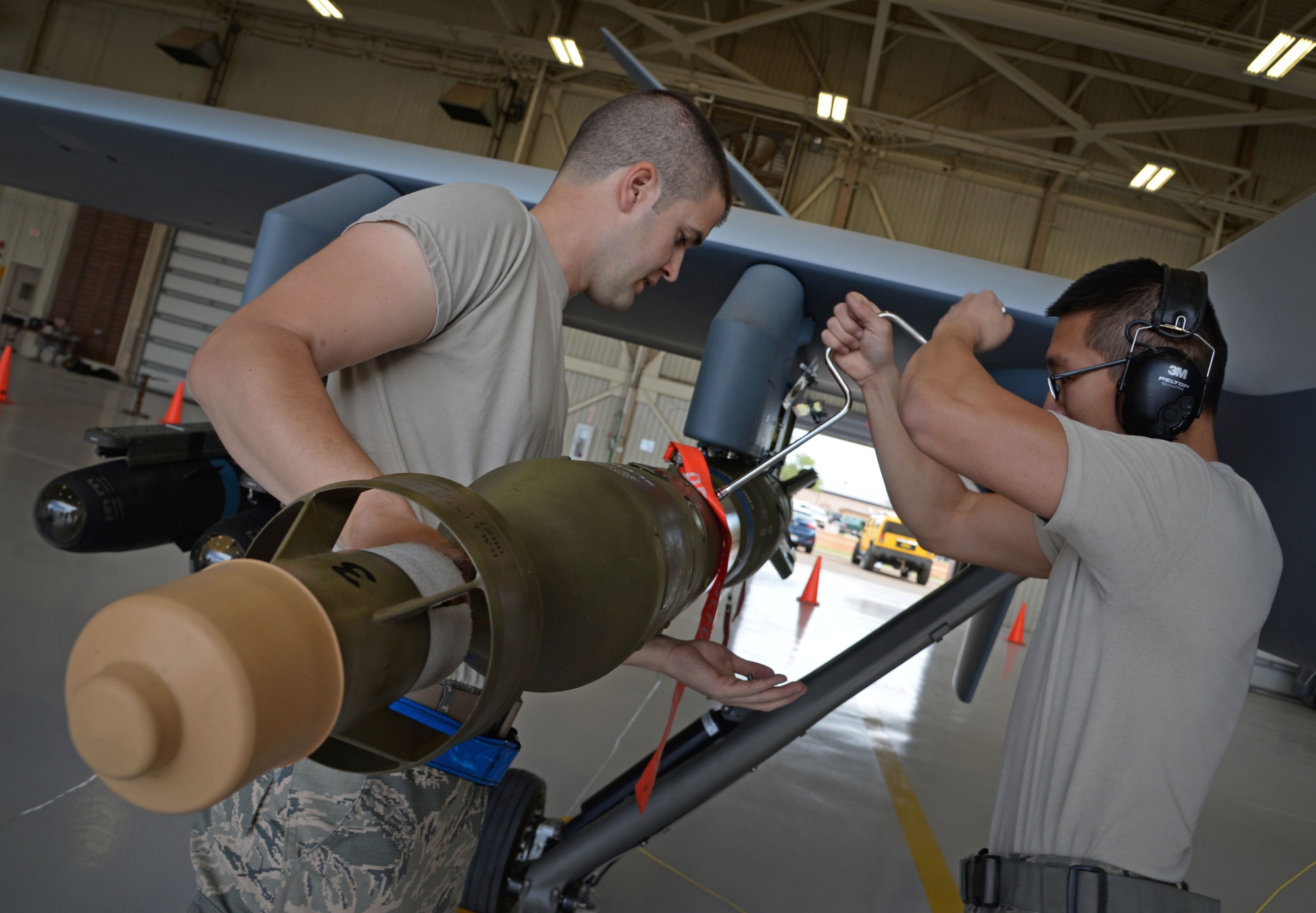 U.S. Air Force Senior Airman Josh Marion and Airman 1st Class Huy Diep, 27th Special Operations Maintenance Squadron MQ-9 Reaper and CV-22 Osprey armament shop, load inert weaponry on an MQ-9 during a load competition April 6, 2015 at Cannon Air Force Base, N.M. Weapons troops expertly loaded MQ-9 Reaper and AC-130W Stinger II platforms simultaneously, providing a real-time look into career field precision, while proving the depth of their unit’s cohesion at the 27th SOW. (U.S. Air Force photo/Staff Sgt. Alex Mercer)