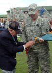 Retired Army General John W. Vessey Jr., with the assistance of 1st Brigade commander Col. Eric Kerska, attaches the meritorious unit streamer to the battalion colors during a ceremony at Camp Ripley, Minn., Aug. 15, 2010. The 1/34th Brigade Special Troops Battalion was awarded the commendation for its exceptionally meritorious conduct during its 1st Brigade Combat Team deployment in 2006.