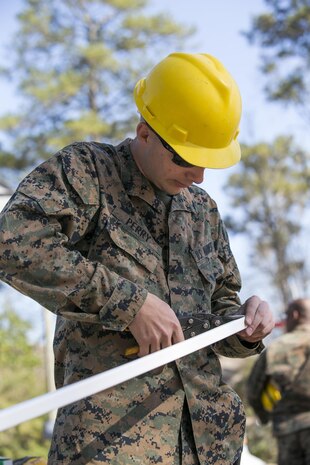 Lance Cpl. Donovan Perry, a combat engineer with 8th Engineer Support Battalion, 2nd Marine Logistics Group, trims J-channel, a material that provides a neat-looking trim for the vinyl siding of a building, aboard Camp Lejeune, N.C., March 31, 2015, during a construction project. Marines with 8th ESB built a storage facility for the unit’s martial arts equipment as training for an upcoming deployment. The Marines will use the same skills to construct schools and other facilities overseas. (U.S. Marine Corps photo by Cpl. Elizabeth A. Case/Released)