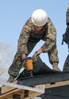 A combat engineer with 8th Engineer Support Battalion, 2nd Marine Logistics Group, nails shingles to the roof of a building aboard Camp Lejeune, N.C., March 31, 2015. Marines with 8th ESB built a storage facility for the unit’s martial arts equipment as training for an upcoming deployment. The Marines will use the same skills to construct schools and other facilities overseas. (U.S. Marine Corps photo by Cpl. Elizabeth A. Case/Released)