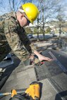 A combat engineer with 8th Engineer Support Battalion, 2nd Marine Logistics Group, trims shingles to the appropriate sizes for the roof of a building aboard Camp Lejeune, N.C., March 31, 2015. Engineers with 8th ESB built a storage facility for the unit’s martial arts equipment as training for an upcoming deployment. The Marines will use the same skills to construct schools and other facilities overseas. (U.S. Marine Corps photo by Cpl. Elizabeth A. Case/Released)