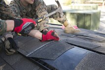A combat engineer with 8th Engineer Support Battalion, 2nd Marine Logistics Group, nails shingles to the roof of a building aboard Camp Lejeune, N.C., March 31, 2015. Marines with 8th ESB built a storage facility for the unit’s martial arts equipment as training for an upcoming deployment. The Marines will use the same skills to construct schools and other facilities overseas. (U.S. Marine Corps photo by Cpl. Elizabeth A. Case/Released)