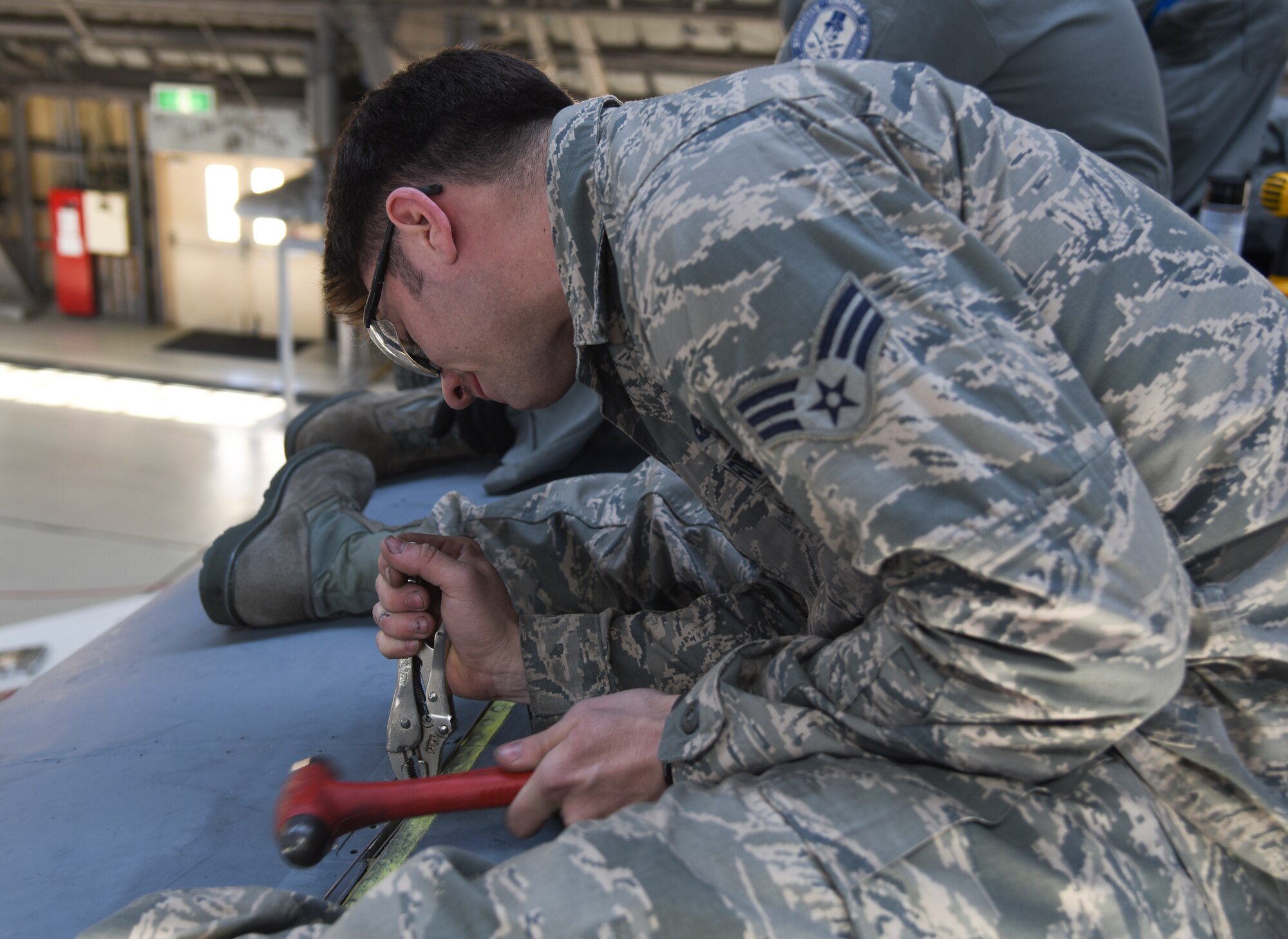 Senior Airman William Smith, 374th Aircraft Maintenance Squadron crew chief, uses a hammer to set a hinge pin inside a leading edge during a rebuild of a C-130 Hercules, number 2067, at Yokota Air Base, Japan, March 11, 2015. Aircraft 2067 suffered damage inside the wings, which resulted in the complete replacement of its internal pieces. Because of this, all the leading edges needed to be removed. (U.S. Air Force photo by Senior Airman Michael Washburn/Released)