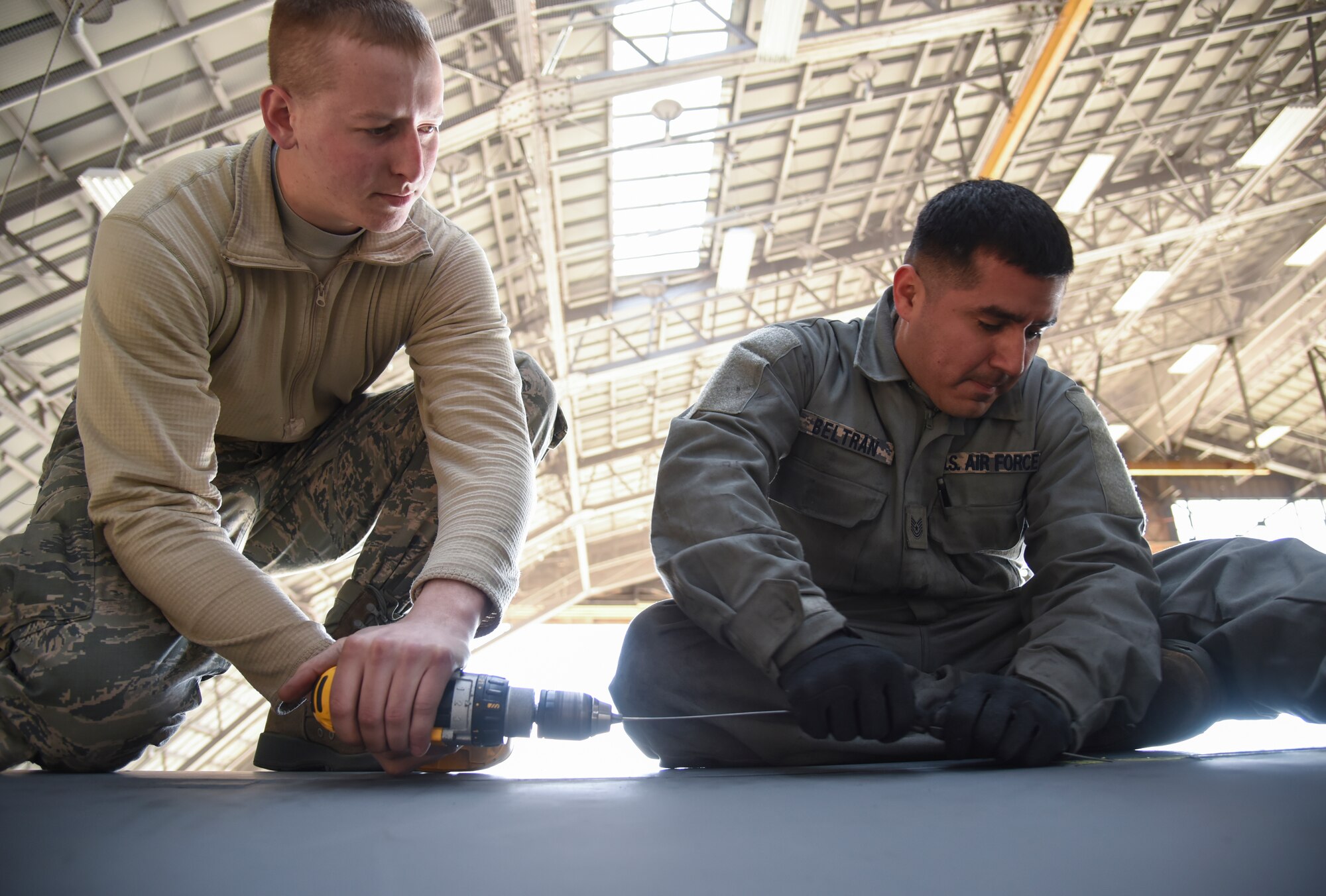 Airman 1st Class Michael Tielleman, 374th Aircraft Maintenance Squadron crew chief (left), and Tech. Sgt. John Beltran, 374 AMXS dedicated crew chief of C-130 Hercules, number 2067, use a power drill to install hinge pins on a leading edge at Yokota Air Base, Japan, March 11, 2015. Tielleman and Beltran were two members of the eight-man team that worked for more than two months on repairing the wings of aircraft 2067. An estimated 5,000 man-hours was spent on the repairs. (U.S. Air Force photo by Senior Airman Michael Washburn/Released)