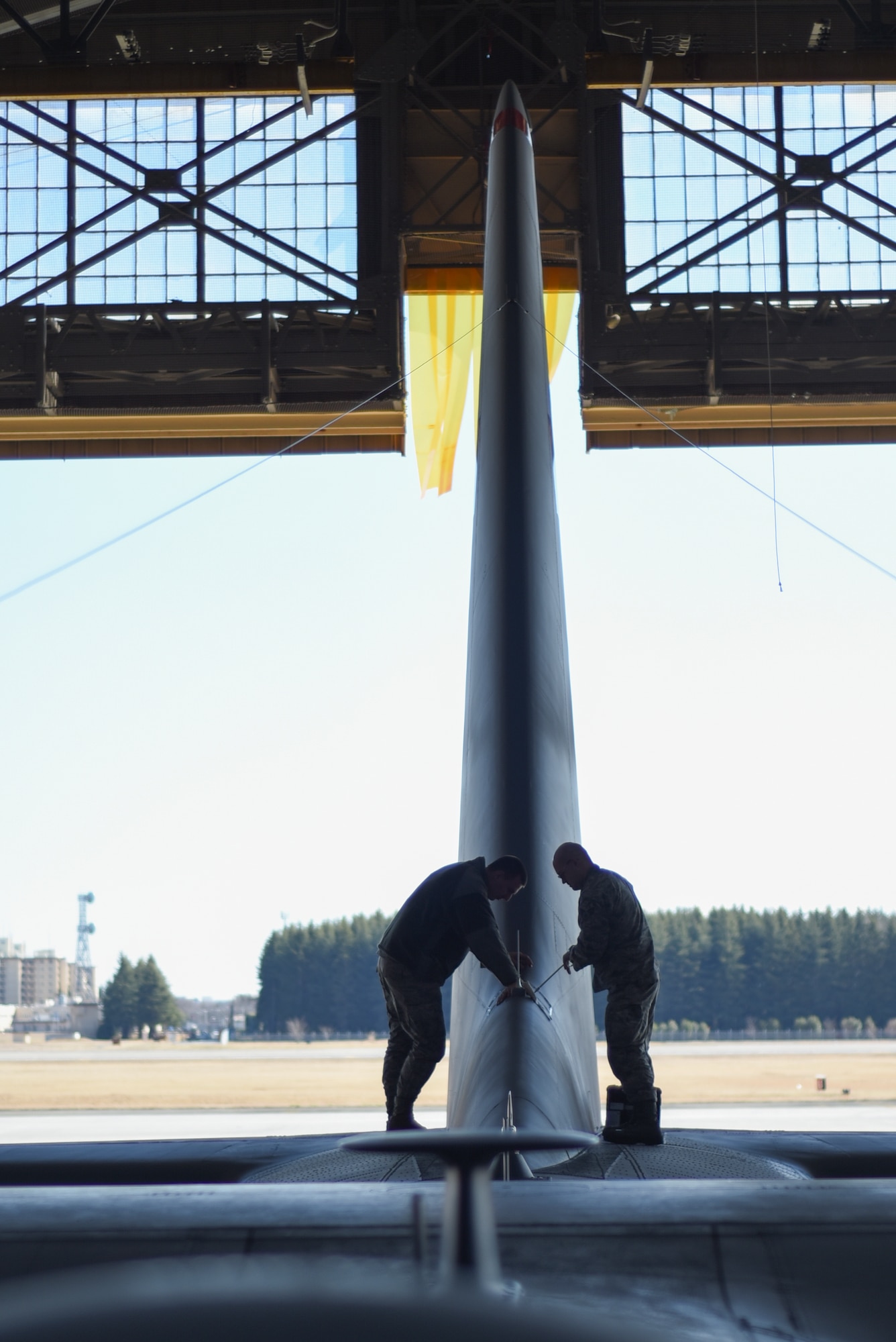 Two Airmen from the 374th Aircraft Maintenance Squadron, work on the tail section of C-130 Hercules, number 2067, at Yokota Air Base, Japan, March 11, 2015. A team of eight Airmen worked on repairing the plane for more than two months. (U.S. Air Force photo by Senior Airman Michael Washburn/Released)