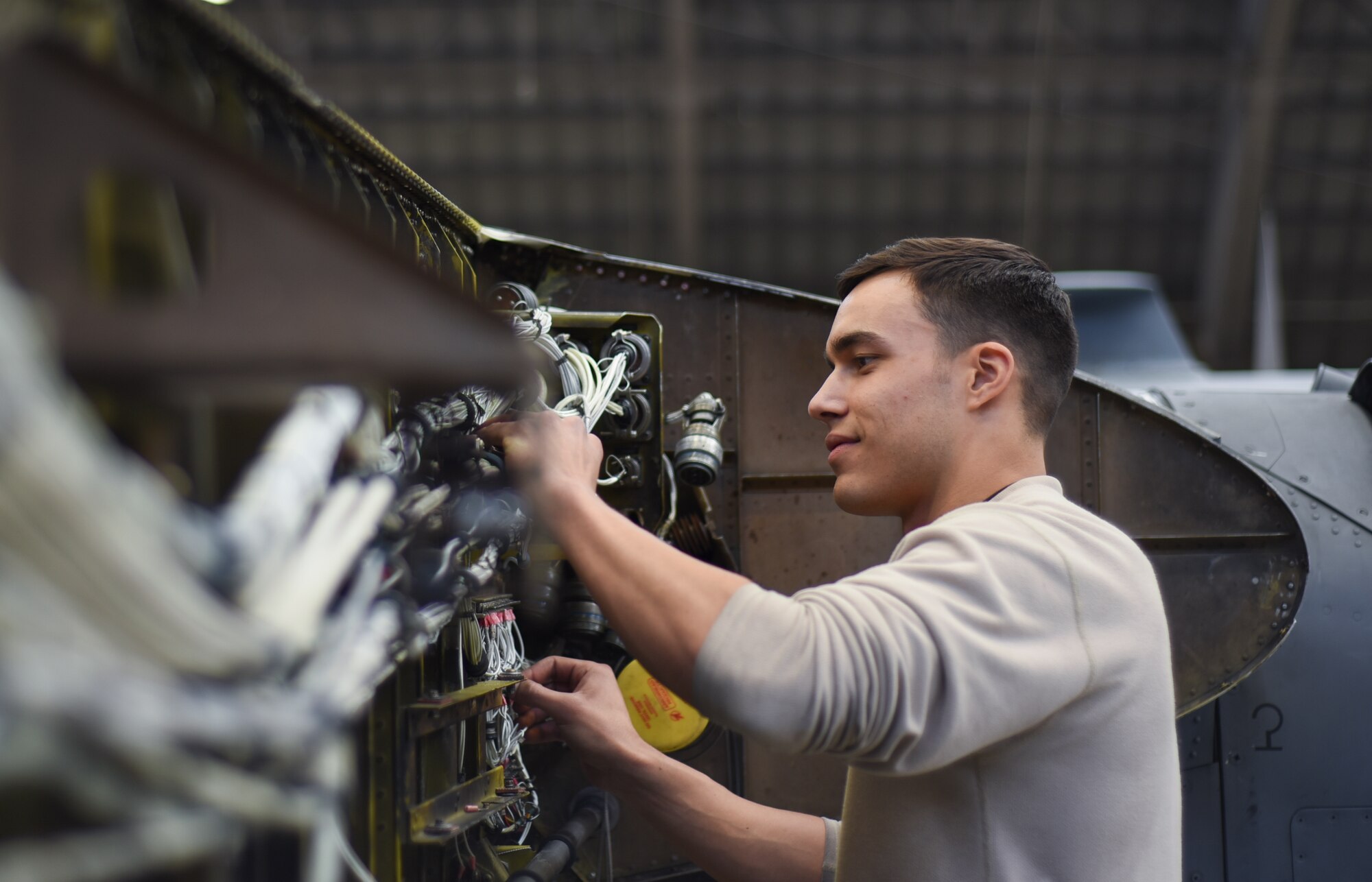 Senior Airman Richard Martinez, 374th Maintenance Squadron electrical and environmental systems, works on an electrical harness routing on C-130 Hercules, number 2067, at Yokota Air Base, Japan, March 5, 2015. The C-130 suffered catastrophic damage to the wing section, which required a complete rebuild. (U.S. Air Force photo by Senior Airman Michael Washburn/Released)
