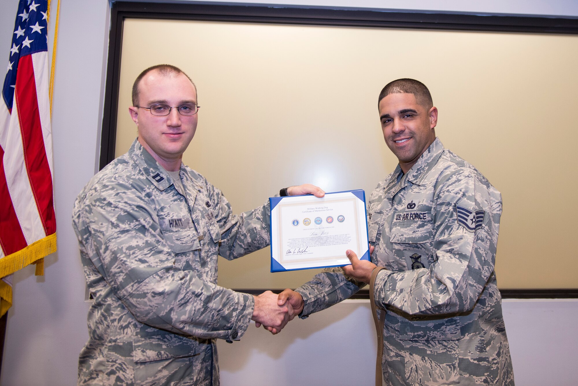 U.S. Air Force Staff Sgt. Anthony Cruz, 23d Security Forces Squadron Military Working Dog handler, receives the Meritorious Service Award from Capt. Tyler Hiatt, 23d SFS operations officer, on behalf of retired MWD Liza during her retirement ceremony April 2, 2015, at Moody Air Force Base, Ga. Cruz was one of seven handlers to take care of Liza since her arrival at Moody AFB. (U.S. Air Force photo by Airman Greg Nash/Released)