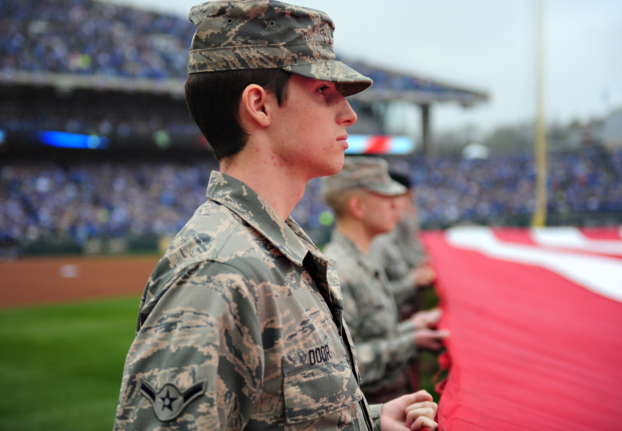 Airman Brandon Door, 509th Communications Squadron client system technician, participates in a flag detail at Kauffmann Stadium April 6, 2015. Airmen from Whiteman Air Force Base, Mo. More than 100 Airmen participated in the detail that was accompanied by the singing of the National Anthem and a B-2 Spirit flyover. (U.S. Air Force photo by Airman 1st Class Joel Pfiester/Released)