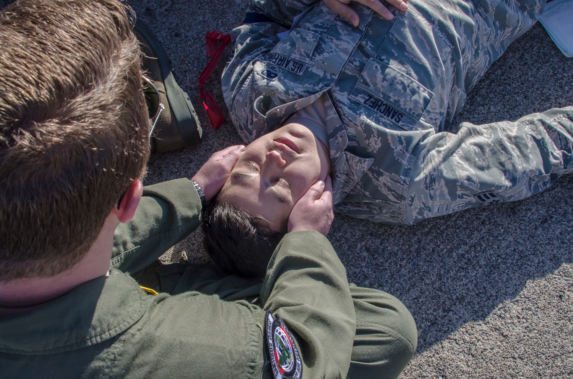 Tech. Sgt. Eric Flanders, the 92nd Air Refueling Squadron standard evaluations NCO in charge, steadies the head of simulated injured role player, Senior Airman Phillip Sanchez, a 92nd Force Support Squadron food apprentice, as part of an emergency management exercise March 30, 2015, at Fairchild Air Force Base, Wash. Exercises like these give Fairchild personnel a chance to experience what is expected during a real world incident and the ability to perform these skills in a safe, training environment. (U.S. Air Force photo/Staff Sgt. Benjamin W. Stratton)