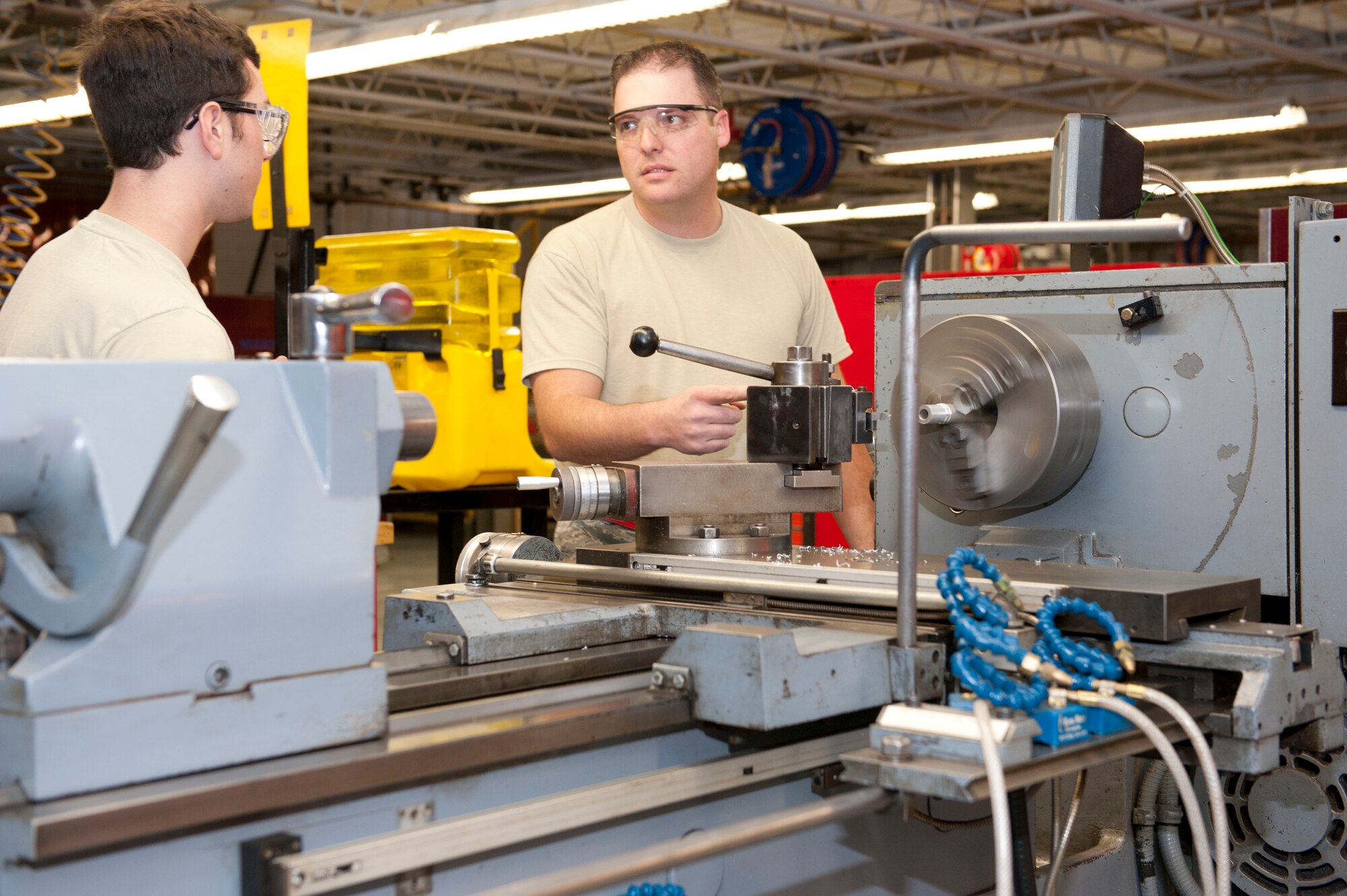 Staff Sgt. Frank Ruckel, 49th Maintenance Squadron Aircraft Metals Technology shift lead, instructs Airman 1st Class Philip Giampaolo, 49th MXS metals tech apprentice, how to make external threads at Holloman Air Force Base, N.M. April 6, 2015. The term used in shop for external threads is turning. (U.S. Air Force photo by Staff Sgt. E’Lysia A. Wray/Released)
