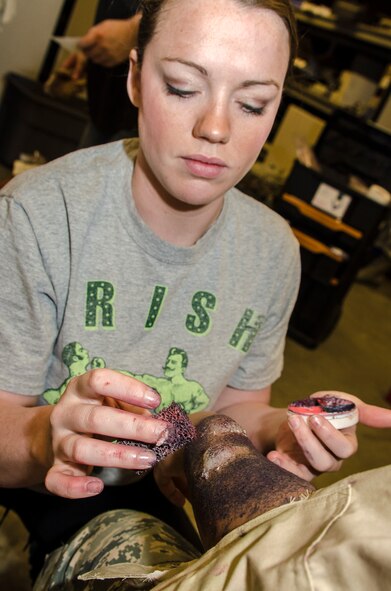 Staff Sgt. Amy Williams, 92nd Aerospace Medicine Squadron certified dental assistant, dabs various types of medical moulage makeup portraying second degree burns to the arm of Airman 1st Class Jauna Williams, a 92nd Force Support Squadron services specialist, as part of an emergency management exercise March 30, 2015, at Fairchild Air Force Base, Wash. To make the exercise appear more realistic, Fairchild “role players” were dressed up in moulage makeup applied to various body parts simulating an array of injuries creating unique emergency response scenarios. (U.S. Air Force photo/Staff Sgt. Benjamin W. Stratton)
