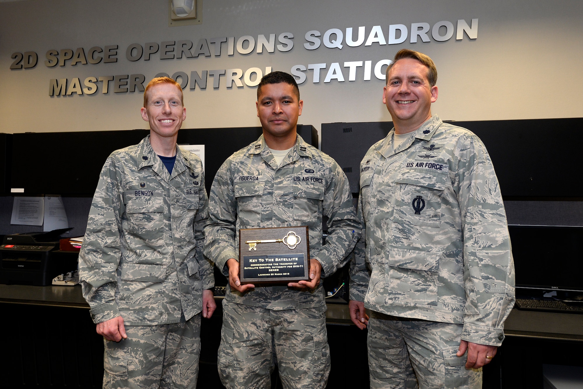 Lt. Col. Todd Benson (left), 2nd Space Operations Squadron commander, and Lt. Col. Sam Baxter (right), 19 SOPS commander, assumes satellite control authority of GPS IIF-9 Satellite Vehicle Number - 71 from Capt. Brian Figueroa (center), Space and Missile Systems Center April 3, 2015, at Schriever Air Force Base, Colo. The vehicle is anticipated to be set ‘healthy to users’ later this month continuing the effort to enhance the precise global positioning navigation and timing services supporting both the warfighter and growing civilian applications. (U.S. Air Force Photo/Christopher Dewitt) 