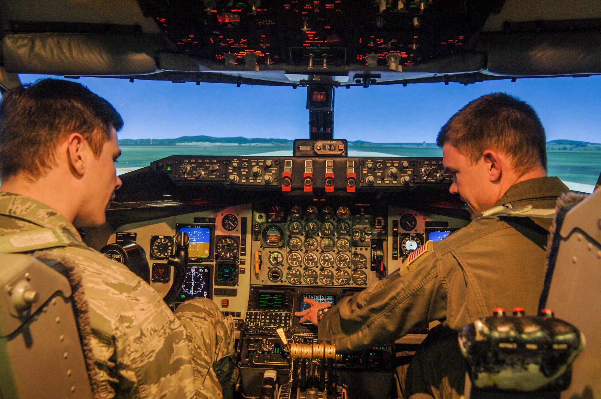 Maj. Daniel (Dan) Schone, 92nd Air Refueling Squadron KC-135 Stratotanker pilot, gives 2nd Lt. Adam Hachtel, 92nd Logistics Readiness Group installation deployment officer, a quick lesson on how to operate the KC-135 flight simulator March 26, 2015 at Fairchild AFB, Wash. CGOs had the chance to “fly” the simulator during the week-long Mission Orientation Brief. 