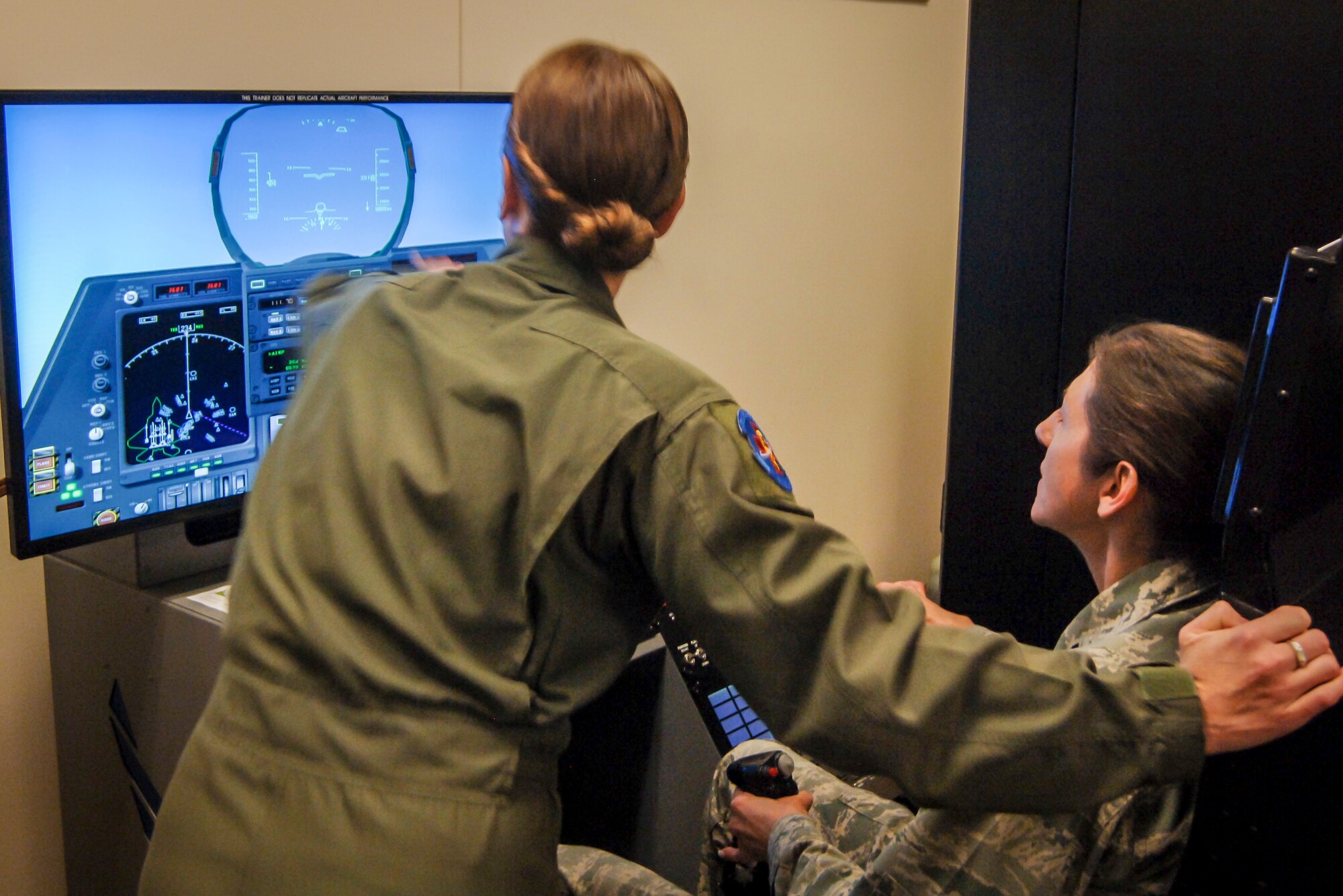 SSgt Bethany Whiteley, 92nd Aerospace Medical Squadron aerospace physiology craftsman, aids Capt. Shelly Hanson, 92nd Medical Group education and training flight commander, as she controls a flight simulator during the CGO Mission Orientation Brief March 24, 2015 at Fairchild AFB, Wash. Aerospace physiology was one of the many stops CGOs made on their tour around the base. (U.S. Air Force photo/2nd Lt. Shelley Gregory)