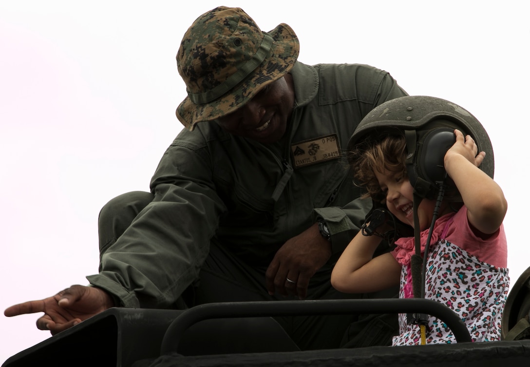Cpl. Jude Exantus, right smiles with a service member's daughter on top of an Assault Amphibious Vehicle April 4 during a United Service Organization Easter celebration on Camp Schwab, Okinawa, Japan. Okinawa children and service members’ children came together to participate in Easter activities, such as egg dyeing, making rabbit masks and an egg hunt. The Camp Schwab USO plans to organize this Easter celebration annually.  Exantus is a native of Ft. Lauderdale, Florida, and AAV crew chief with Combat Assault Battalion, 3rd Marine Division, III Marine Expeditionary Force. 