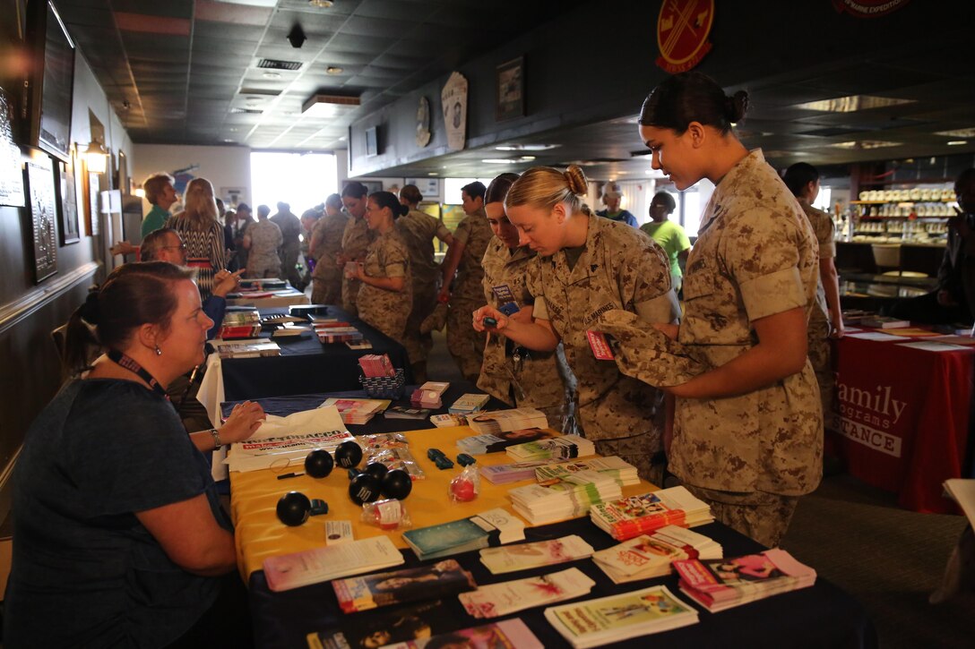 Female Marines look at brochures of information during the education fair at the fourth annual Vivian A. Holmes Female Marine Symposium at Marine Corps Air Station New River, N.C., March 26, 2015. During the symposium, female Marines received informational classes, participated in guided discussions and attended an education-station fair to get information on resources directly related to female Marines and their families. 