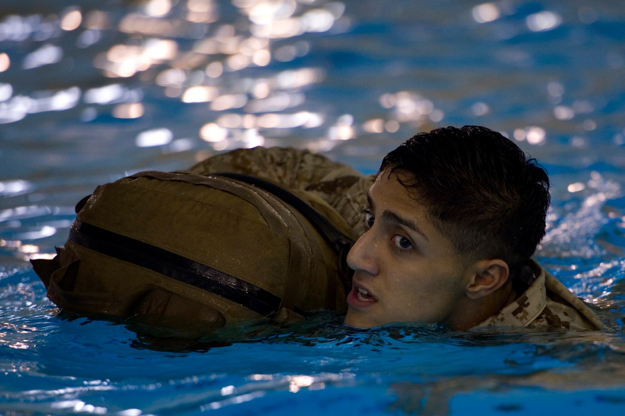 U.S. Marine Corps Lance Cpl. Daniel Dilego, Detachment 1, Communication Company, Combat Logistics Regiment 45, 4th Marine Logistics Group wireman, uses his pack to help him swim during the 25-meter pack-swim portion of the Marine Corps water survival training program basic qualification at Great Lakes Naval Station, Ill., March 21, 2015.  Marines are required to complete basic level of qualifications every two years and can progress to advanced levels of training on a voluntary basis. (U.S. Air Force photo/Tech. Sgt. Benjamin Mota)