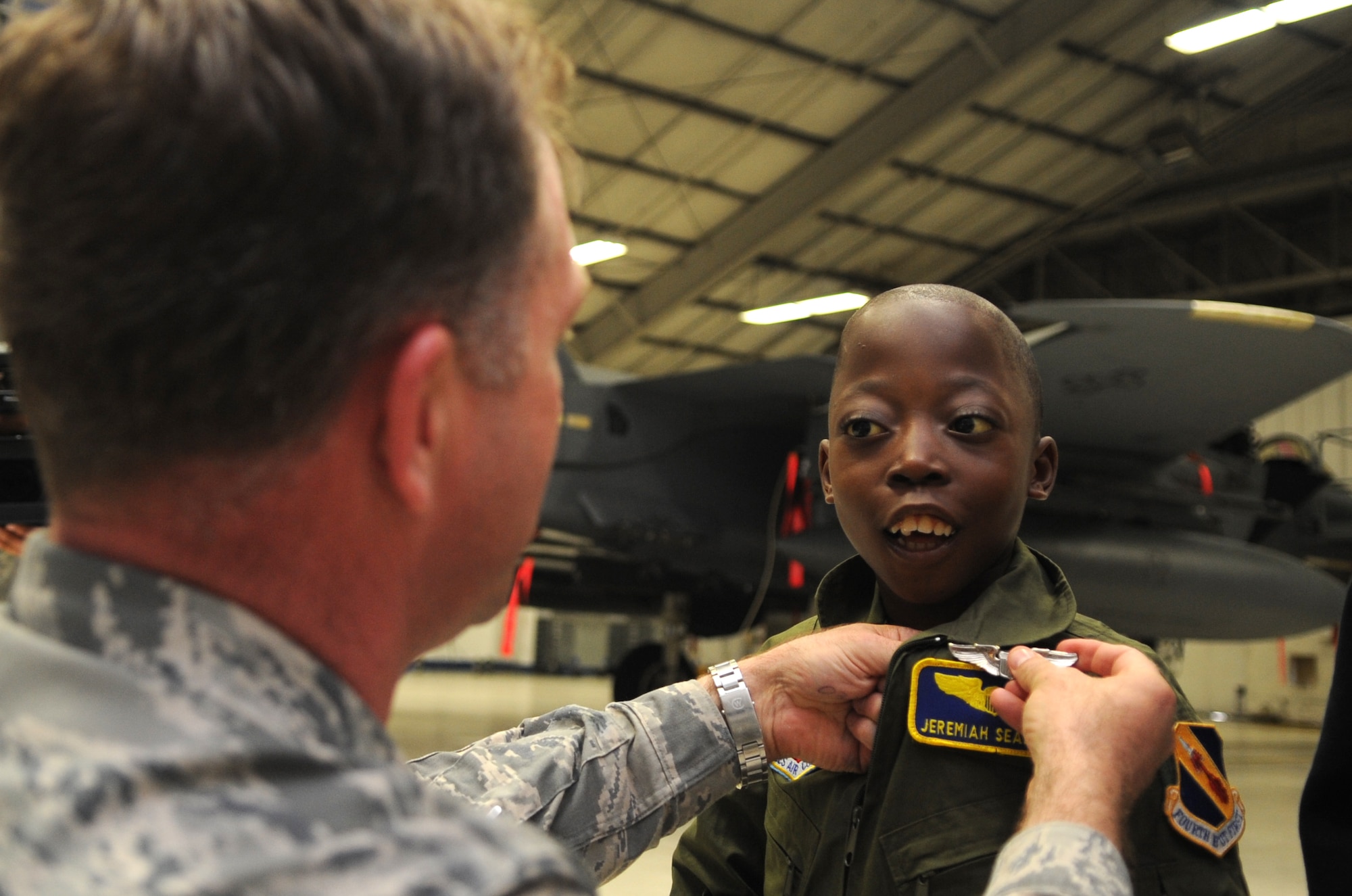 Col. Mark Slocum, 4th Fighter Wing commander, pins wings on Jeremiah Seaberry, 334th Fighter Squadron pilot for a day, during a 4th FW Pilot for a Day event, April 3, 2015, at Seymour Johnson Air Force Base, North Carolina. Earning wings is a milestone for all pilots, symbolizing the completion of their training. (U.S. Air Force photo/Senior Airman Ashley J. Thum)