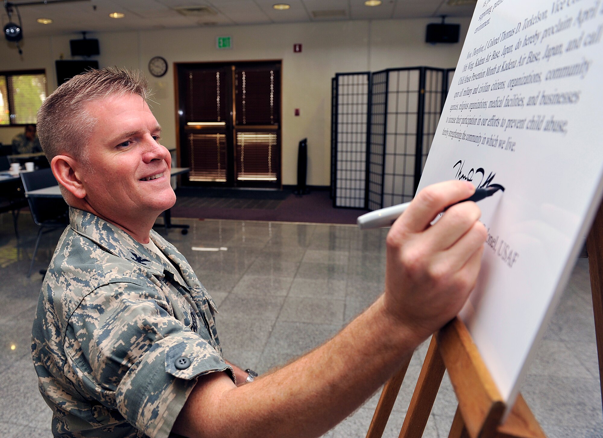 U.S. Air Force Col. Thomas Torkelson, 18th Wing vice commander, signs a Child Abuse Prevention Month proclamation at the Schilling Community Center on Kadena Air Base, Japan, April 8, 2015. April is Child Abuse Prevention Month and Month of the Military Child; throughout the month the 18th Medical Operations Squadron Family Advocacy staff has several events planned that will help the Kadena community raise awareness about child abuse. (U.S. Air Force photo by Naoto Anazawa)