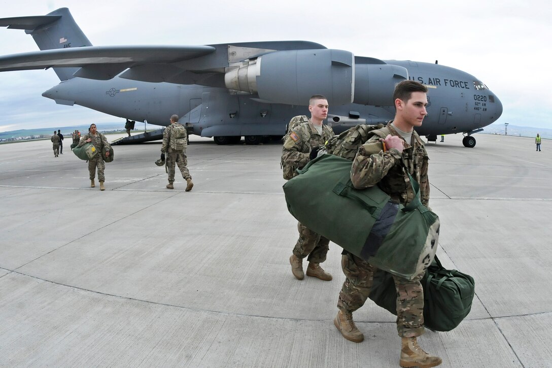 U.S. soldiers walk on the flight line toward their Stryker Combat Vehicle after arriving and unloading equipment at Burgas Airport in Burgas, Bulgaria, March 29, 2015.