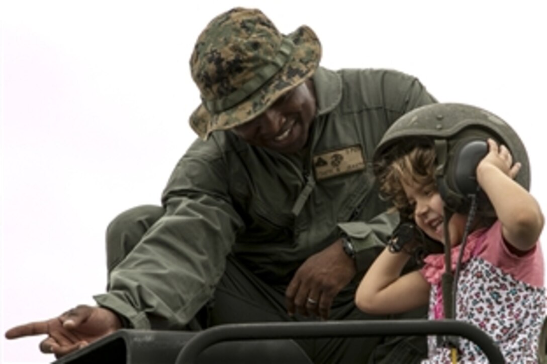 U.S. Marine Corps Cpl. Jude Exantus shows a child an assault amphibious vehicle during a USO Easter celebration on Camp Schwab in Okinawa, Japan, April 4, 2015. Exantus is a crew chief assigned to Combat Assault Battalion, 3rd Marine Division, III Marine Expeditionary Force.
