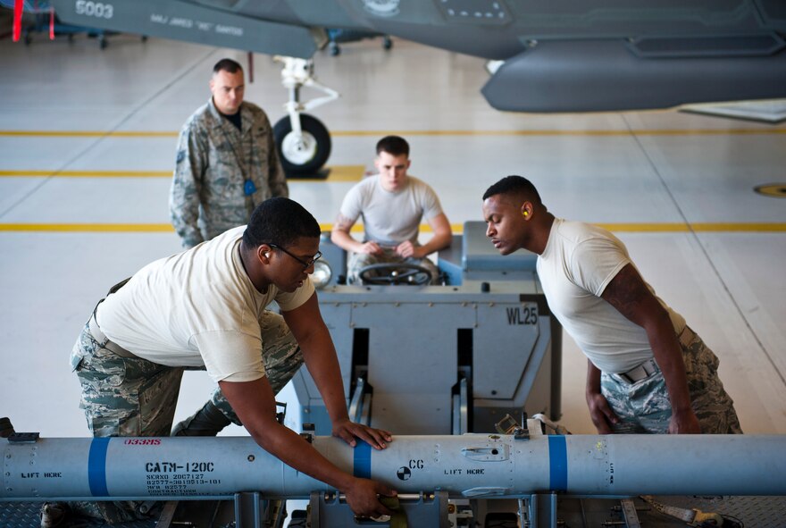 Staff Sgt. Timothy Gaulden, front left, 58th Aircraft Maintenance Unit crew six load crew chief, and Airman 1st Class John St. Cyr, 58 AMU crew six load crew member, guide an AIM-120 Advanced Medium-Range Air-to-Air Missile on to an MJ-1 lift truck during a weapons load competition on Eglin Air Force Base, Florida, April 3, 2015. During weapons load competitions, crews are evaluated on how well they load munitions safely, efficiently and in a timely manner as a team.  (U.S. Air Force Photo/Staff Sgt. Marleah Robertson)