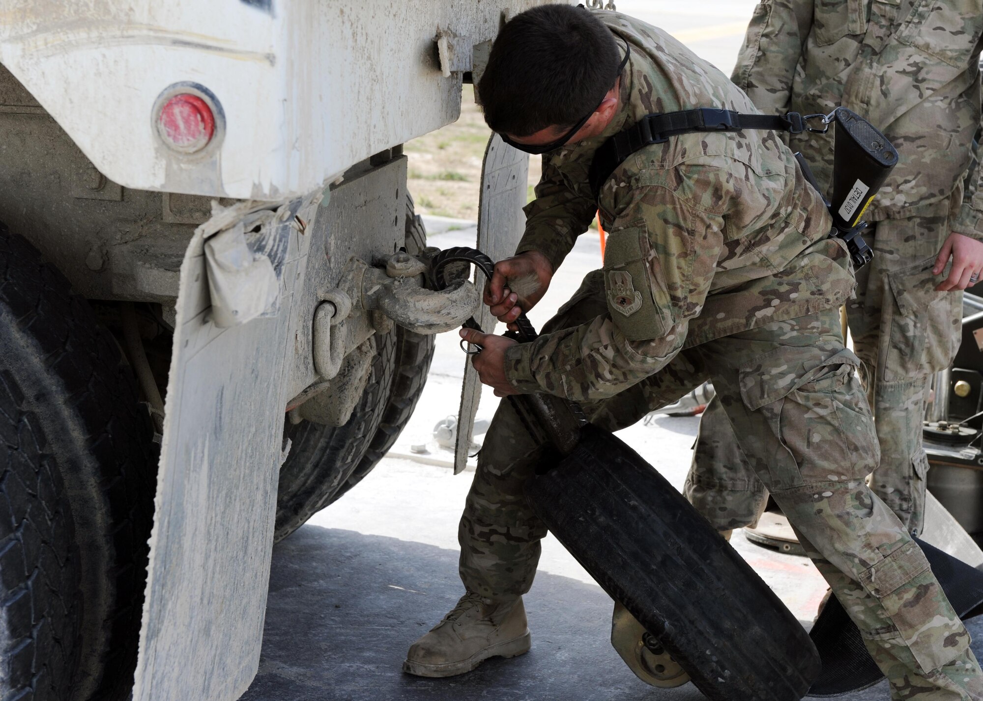 U.S. Air Force Senior Airman Bob Roberts, 455th Expeditionary Civil Engineer Squadron power production journeyman, attaches a tire to a truck prior to testing a Mobile Aircraft Arresting System March 18, 2015 at Bagram Airfield, Afghanistan. The MAAS was from a separate taxiway as part of the construction of an alternate runway at Bagram. (U.S. Air Force photo by Staff Sgt. Whitney Amstutz/released)