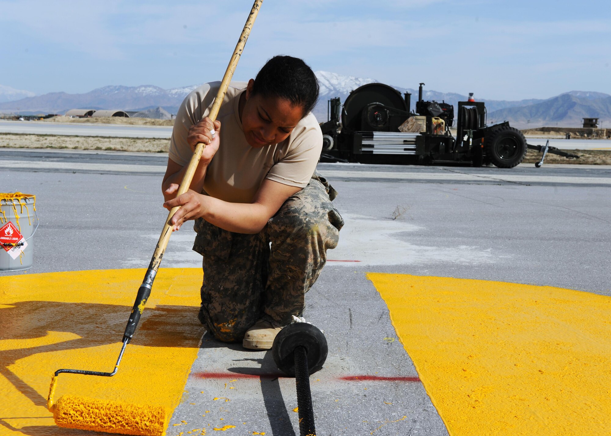 U.S. Air Force Senior Airman Ariel Graham, 455th Expeditionary Civil Engineer Squadron force protection, paints runway markers on a flightline March 18, 2015 at Bagram Airfield, Afghanistan. The markers were painted on Taxiway Zulu as part of its conversion from a taxiway to a runway. (U.S. Air Force photo by Staff Sgt. Whitney Amstutz/released)