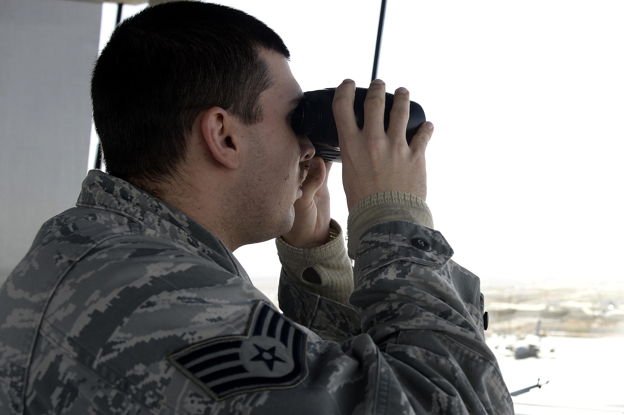 Staff Sgt. Matt, air traffic control liaison, scans the flightline from the air traffic control tower at an undisclosed location in Southwest Asia April 3, 2015. The duties of an air traffic controller liaison include making an automated terminal information service, which is a continuous broadcast of recorded weather and any other pertinent information for the pilots that they listen to before they go out. Matt is currently deployed from Tyndall Air Force Base, Fla. (U.S. Air Force photo/Tech. Sgt. Marie Brown/RELEASED)

