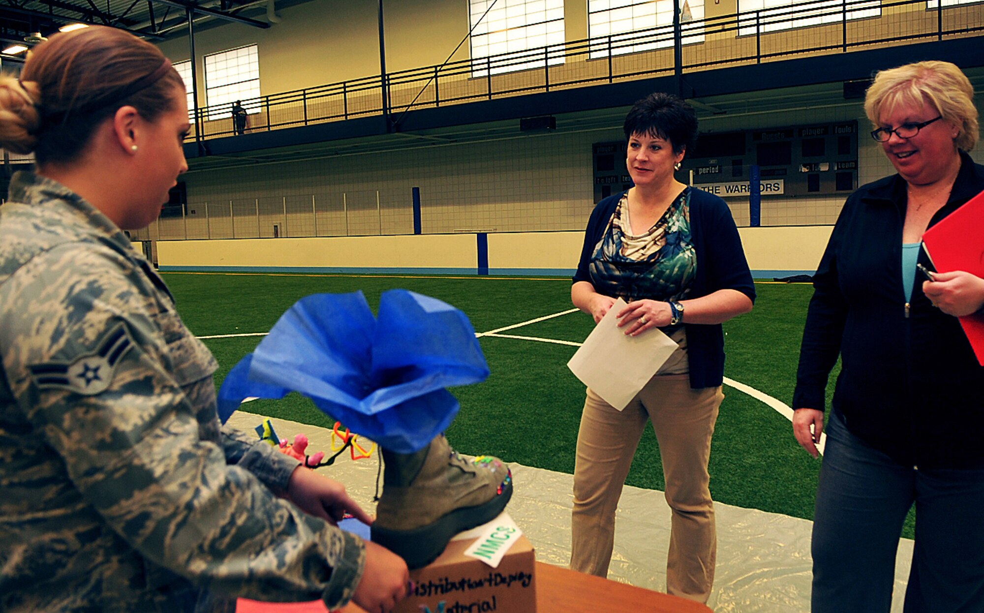 Airman 1st Class Ashley Smith, 319th Logistics Readiness Squadron traffic management journeyman, speaks to judges, Keri Kerr, left, Grand Forks Community Violence Intervention Center (CVIC) director of community innovations, and Sue Grollimund, 319th Air Base Wing Sexual Assault Prevention and Response assistant during the Sexual Assault Awareness and Prevention Day of Action boot decorating contest on Grand Forks Air Force Base, N.D., April 7, 2015. Grand Forks AFB and the CVIC have worked together to address issues of victimization since 1998. (U.S. Air Force photo/Airman 1st Class Bonnie Grantham/released)