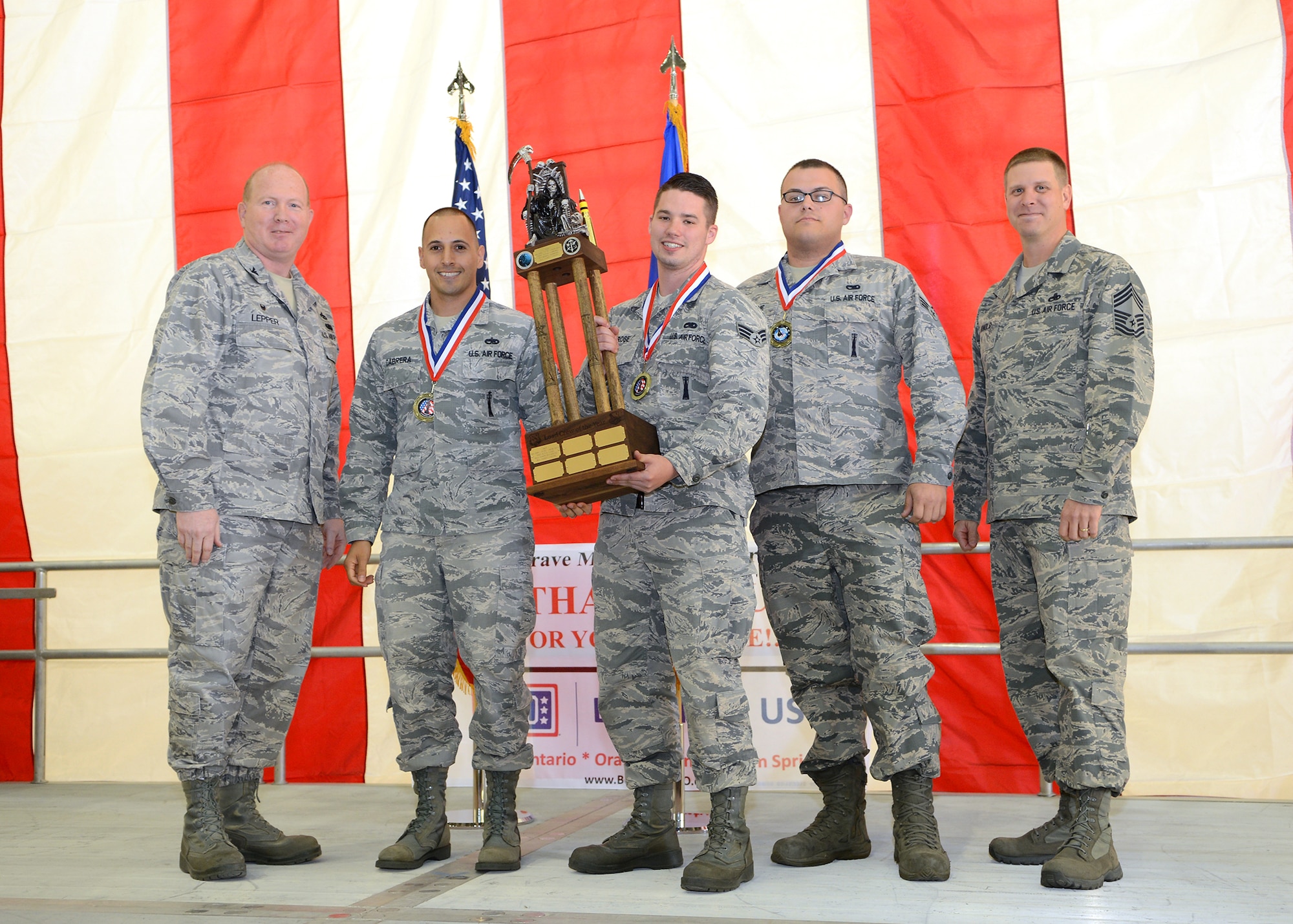 (Far left) Col. Robert Lepper, 412th Maintenance Group commander, and (far right) Chief Master Sgt. Kennon Arnold, 412th MXG command chief, present the Joint Strike Fighter Crew-DT1 with the 2014 Weapons Load Crew of the Year award during the 412th Maintenance Group Maintenance Professional of the Year banquet held April 6 at Hangar 1600. The banquet, hosted by the 412th MXG, was held to recognize award recipients in the 2014 Maintenance Group Annual Award category, the 2014 Lt. Gen. Leo Marquez Award category and 2014 Maintenance Professionals of the Year category. (U.S. Air Force photo/Jet Fabara)