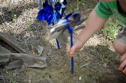 A child plants a pinwheel in the ground for Child Abuse Prevention Month on April 8, 2015 at the Karen Scott Heath Child Development Center on Joint Base Charleston – Weapons Station, S.C. Pinwheel gardens represent the effort to focus on community activities that support families and public policies prioritizing prevention of  child abuse and neglect. (U.S. Air Force photo/Staff Sgt. AJ Hyatt)