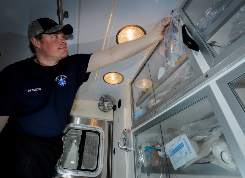 Cary Kehr, 5th Medical Operations Squadron paramedic, hangs an IV bag in the back of an ambulance on Minot Air Force Base, N.D., March 30, 2015. Kehr and other civilian paramedics in his section work 24 to 72 hour shifts supporting the medical needs of base Airmen and their families. (U.S. Air Force photo/Senior Airman Stephanie Morris)