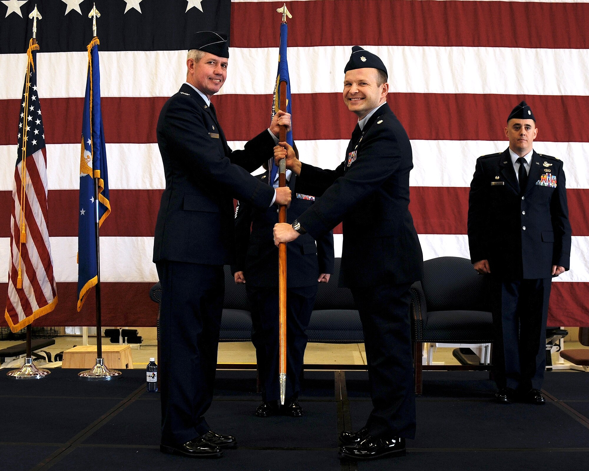 Col. James Boster, 14th Operations Group Commander, passes the 14th Operations Support Squadron guidon to Lt. Col. Matthew Baugh, the new 14th OSS Commander during a change of command ceremony April 9 at the McAllister Fire Station on Columbus Air Force Base, Mississippi. Baugh was previously the Director of Operations for the 50th Flying Training Squadron on Columbus AFB, Mississippi. (U.S. Air Force photo/Sharon Ybarra)