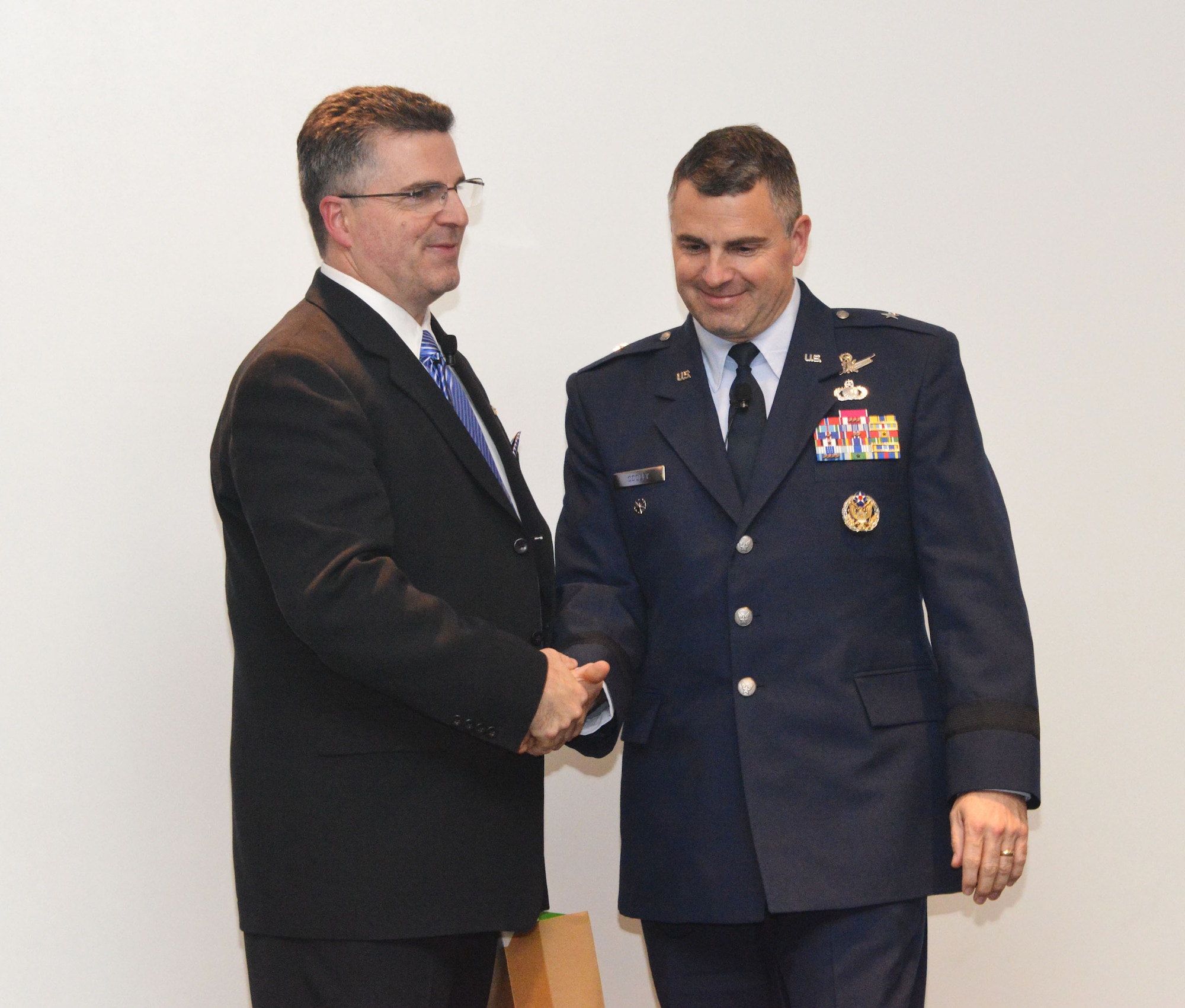 At his promotion ceremony Tom Cooley, left, shakes hands with his brother, Brig. Gen. William Cooley. Tom was promoted to an ST, or scientific professional, the highest rank a technical leader can achieve, considered to be the civilian equivalent of general. (Photo by Dennis Carlson)