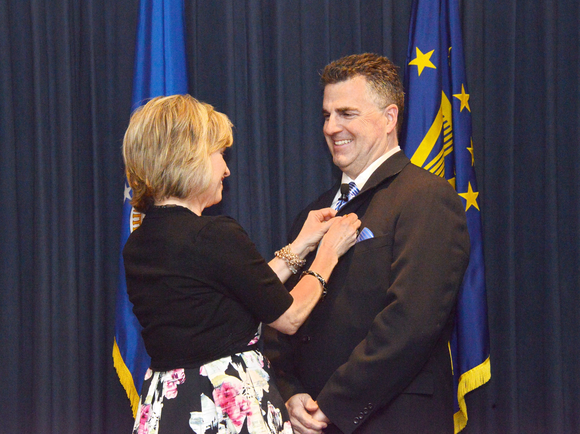 Mary Cooley pins on her husband, Thomas, the insignia of his new designation as an ST, or scientific professional. It is the highest rank a technical leader can achieve, considered to be the civilian equivalent of general. (Photo by Dennis Carlson)