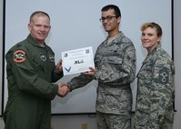 Airman 1st Class Victor Roman, center, 47th Communications Squadron cyber transport journeyman, poses with Col. Darrell Judy, 47th Flying Training Wing vice commander and Chief Master Sgt. Teresa Clapper, 47th FTW command chief, after accepting the XLer of the week award here April 2, 2015. The XLer is a weekly award chosen by wing leadership and was presented to Roman for his work in monitoring 125 network components for system availability and negative trends by using the Network Management System. (U.S. Air Force photo by Airman 1st Class Jimmie D. Pike)(Released)