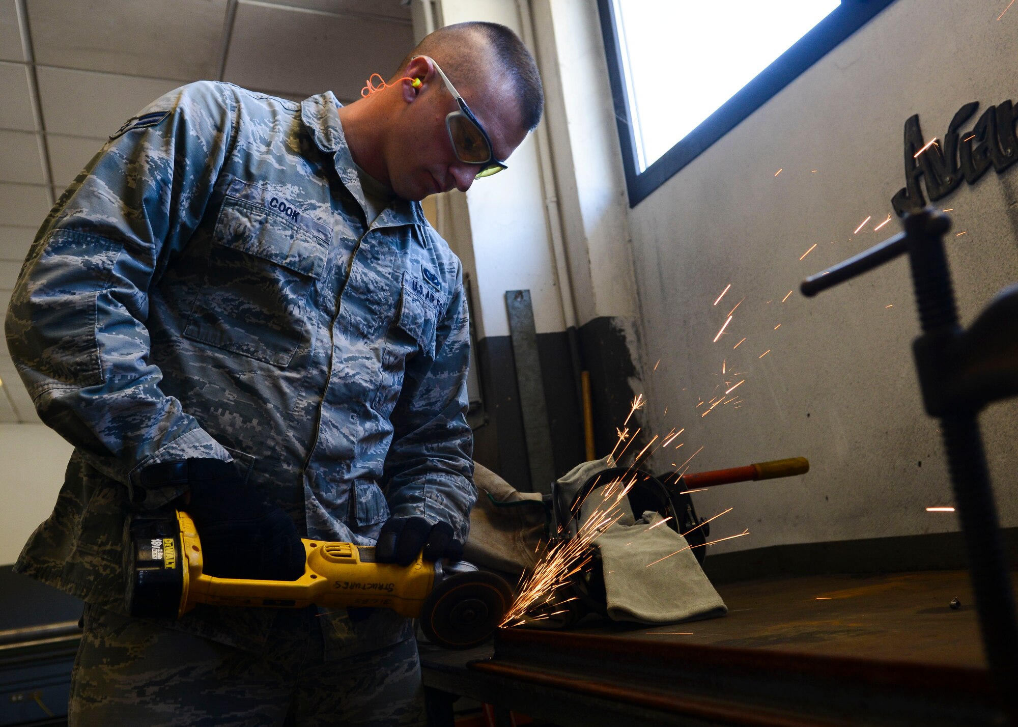 U.S. Air Force Airman 1st Class Adam Cook, 31st Civil Engineer Squadron structural journeyman, grinds a jagged edge on a metal T-bar segment April 7, 2015, at Aviano Air Base, Italy. Most of the metal work performed by structures Airmen revolves around air ducts, but they also work with hangar doors, metal supports and signs. (U.S. Air Force photo by Senior Airman Austin Harvill/Released)