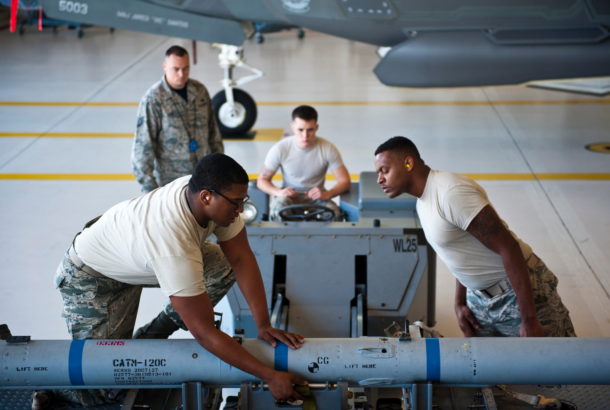 Staff Sgt. Timothy Gaulden, front left, 58th Aircraft Maintenance Unit crew six load crew chief, and Airman 1st Class John St. Cyr, 58 AMU crew six load crew member, guide an AIM-120 Advanced Medium-Range Air-to-Air Missile on to an MJ-1 lift truck during a weapons load competition on Eglin Air Force Base, Florida, April 3, 2015. During weapons load competitions, crews are evaluated on how well they load munitions safely, efficiently and in a timely manner as a team. (U.S. Air Force Photo/Staff Sgt. Marleah Robertson)