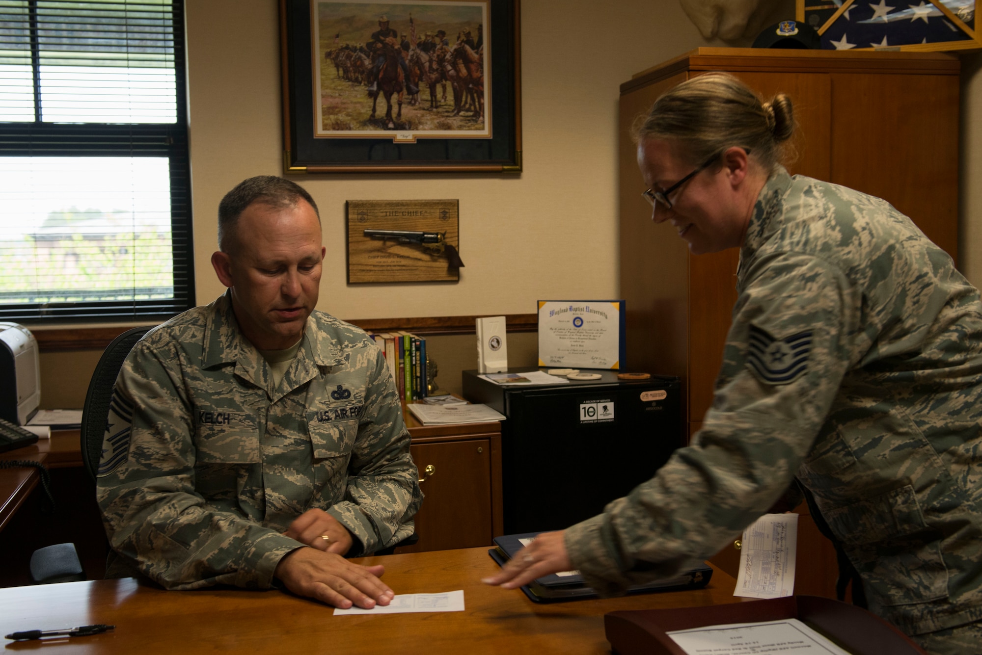 U.S. Air Force Chief Master Sgt. David Kelch, 23d Wing command chief, returns an Air Force Assistance Fund registration form to Tech. Sgt. Sabrena Depew, 23d Wing administrative support and AFAF squadron keyworker, April 7, 2015, at Moody Air Force Base, Ga. Airmen can contribute donations to the Air Force Aid Society, the Air Force Enlisted Village, the Air Force Villages and the General and Mrs. Curtis E. Lemay Foundation. (U.S. Air Force photo by Airman 1st Class Dillian Bamman/Released)