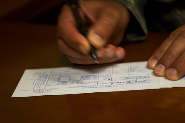 U.S. Air Force Chief Master Sgt. David Kelch, 23d Wing command chief, signs an Air Force Assistance Fund registration form April 7, 2015, at Moody Air Force Base, Ga. The AFAF is a non-profit organization that aids active duty Airmen, retirees, reservists, guardsmen and their families in times of financial need. (U.S. Air Force photo by Airman 1st Class Dillian Bamman/Released)