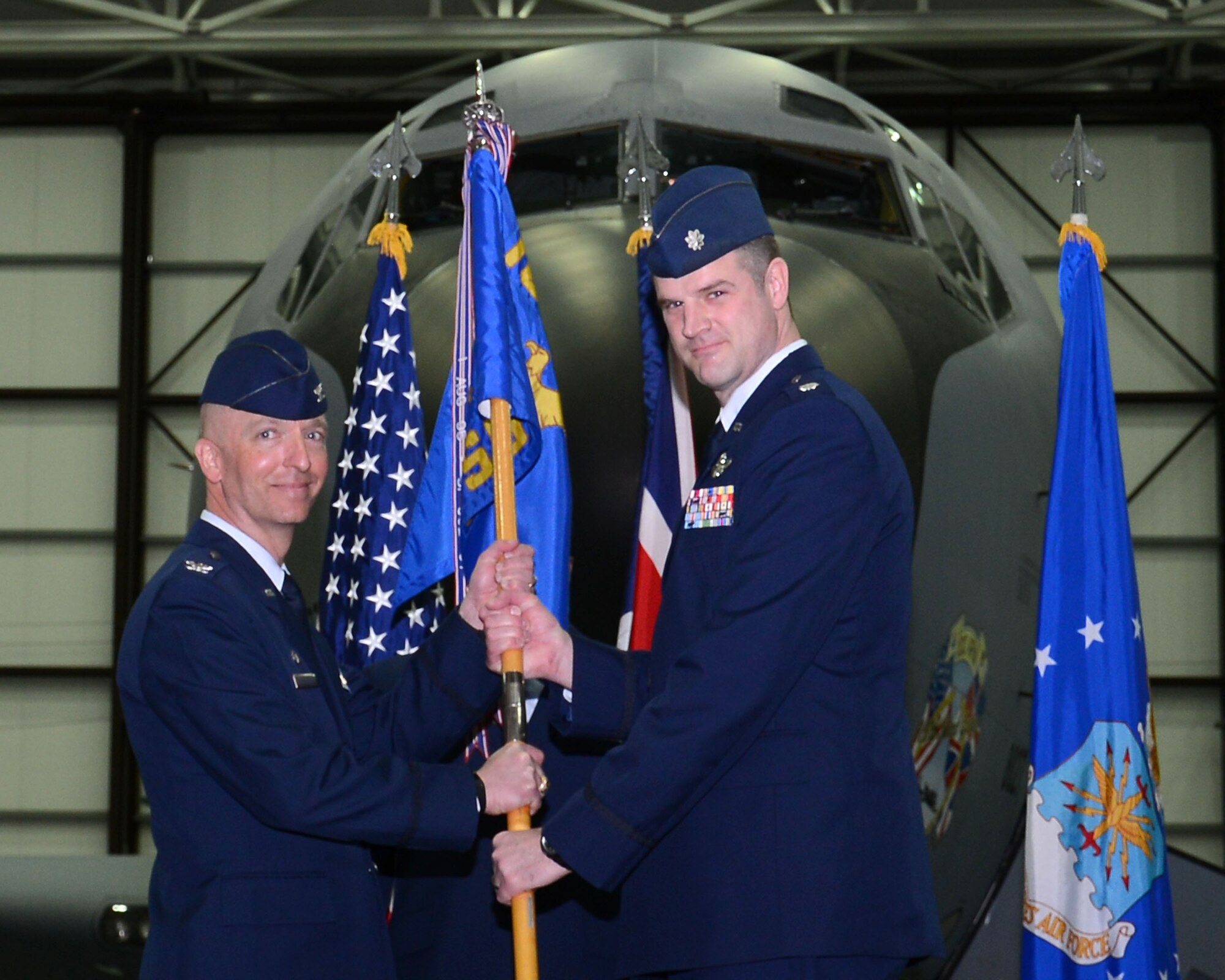 U.S. Air Force Col. Noel Bradford, left, 100th Operations Group commander, passes the 100th Operations Support Squadron guidon to U.S. Air Force Lt. Col. Jay Butterfield, incoming 100th OSS commander, during the 100th OSS change of command ceremony April 2, 2015, on RAF Mildenhall, England. The passing of the unit guidon during a change of command ceremony is a symbolic representation of passing authority to the incoming commander. (U.S. Air Force photo by Gina Randall/Released)