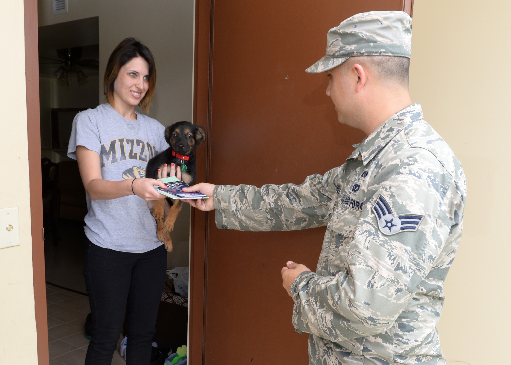 Senior Airman Louie Quintanilla, 36th Civil Engineer Squadron emergency manager, hands out natural disaster preparation materials to a military family housing April 7, 2015, at Andersen Air Force Base, Guam. The 36th CES Emergency Management Flight will be holding events to better educate and prepare Andersen Airmen for natural disasters during the month of April. (U.S. Air Force photo by Airman 1st Class Joshua Smoot/Released)