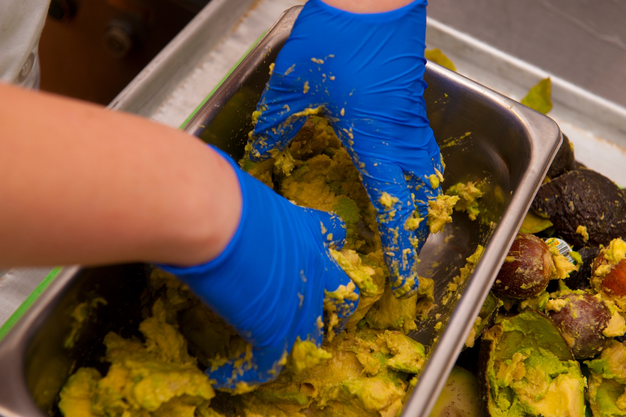 Airman 1st Class Kalen Van Volkenburg, Services specialist, peels and smashes avocado to be served during lunch at the Shifting Sands Dining Facility on Holloman Air Force Base, N.M., April 8, 2015. Force Support Squadrons oversee areas such as the dining facilities, lodging, mortuary affairs, military personnel sections and fitness facilities. Van Volkenburg who has been in the services career field  for over two years recalls her time as a civilian as being very slow paced compared to being an Airman. Her father, a retired U.S. Air Force Senior Master Sgt. was her inspiration for joining, seeing his dedication and hard work throughout her childhood gave her strong ties to the military and the Air Force. (U.S. Air Force photo by Senior Airman Chase Cannon/ Released)