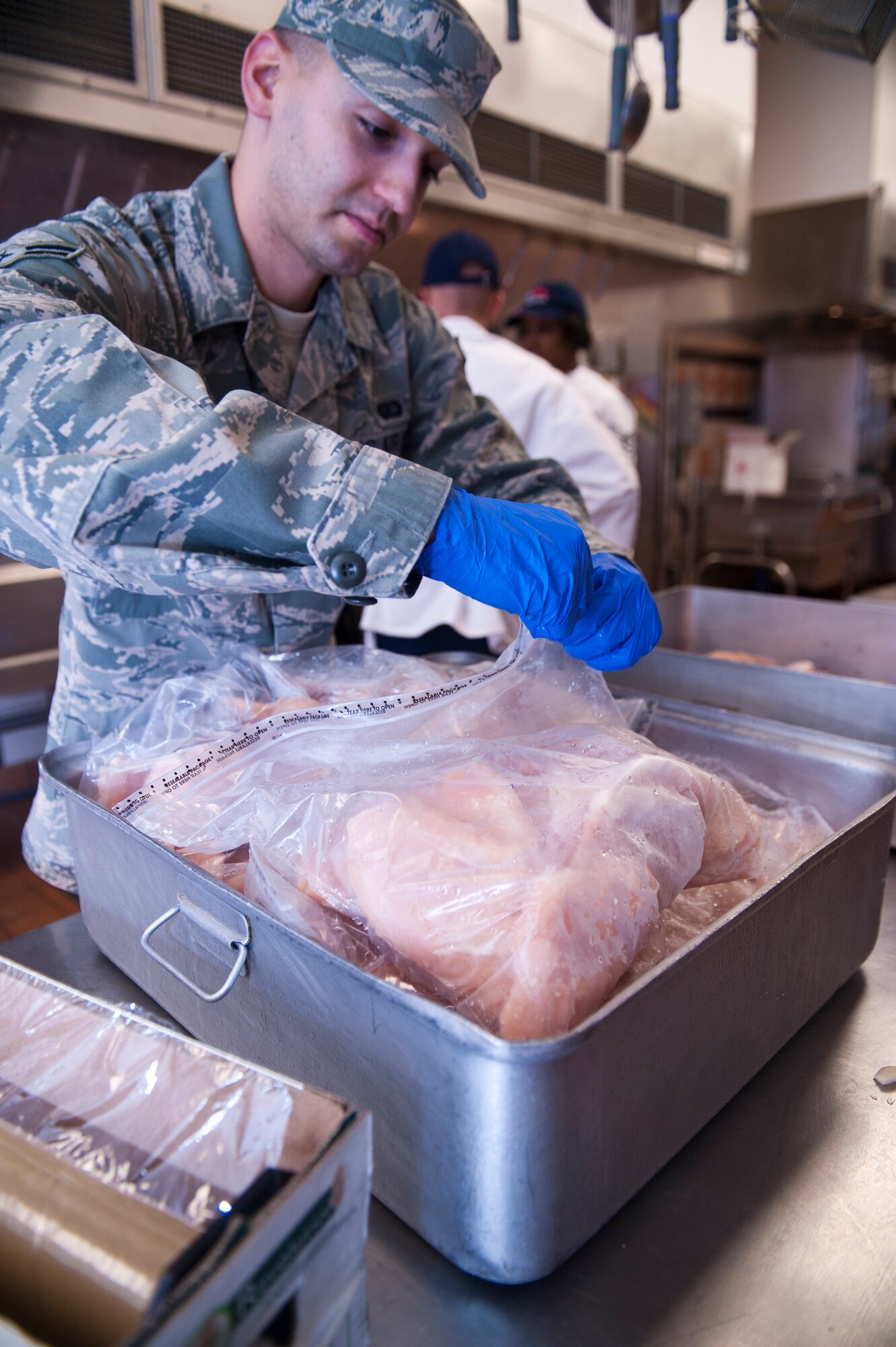Airman 1st Class Michael Baez, Services specialist, prepares chicken to thaw for lunch at the Shifting Sands Dining Facility at Holloman Air Force Base, N.M., April 8, 2015. Force Support career fields ensure military members are properly taken care of by literally feeding the fight. Force Support oversees areas such as the dining facilities, lodging, mortuary affairs and fitness facilities. Baez is one of the newest members in the Air Force, graduating from primary technical training just over a month ago. With his personal ideals of dedication, hard work and a desire to make a difference Baez lives the Air Force core values of integrity first, service before self, and excellence in all we do.  (U.S. Air Force photo by Senior Airman Chase Cannon/ Released)