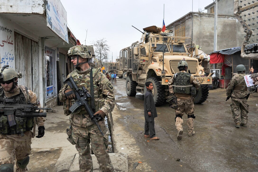 U.S. and Czech soldiers provide security around their mine-resistant, ambush-protected vehicles and await other soldiers' return from a meeting with the Bagram district governor in Bagram, Afghanistan, March 26, 2015.