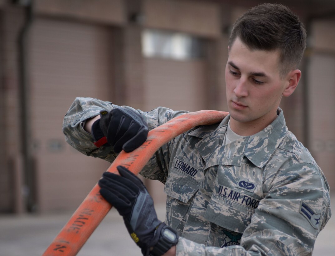 U.S. Air Force Airman 1st Class Alex Leonard, 27th Special Operations Civil Engineer Squadron firefighter, drains water from a fire hose April 8, 2015 at Cannon Air Force Base, N.M. Water must be properly drained to minimize molding and increase longevity of equipment. (U.S. Air Force photo/Staff Sgt. Alex Mercer) 
