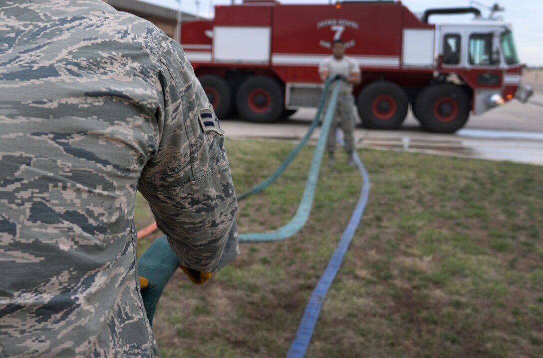 U.S. Air Force Airman 1st Class Tyler Foster and Staff Sgt. Rodney Welch, 27th Special Operations Civil Engineer Squadron firefighters, untangle a fire hose after ops checks April 8, 2015 at Cannon Air Force Base, N.M. If the hose it stored properly, firefighters can more easily access the equipment in the event of an emergency. (U.S. Air Force photo/Staff Sgt. Alex Mercer) 
