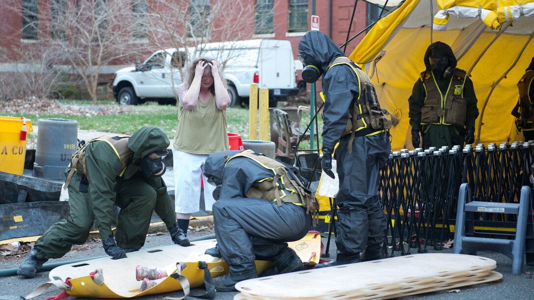 Marines from the decontamination platoon put a child pretending to be injured on a backboard during Exercise Silent Ghost outside St. Elizabeths East hospital in Washington, D.C. April 7, 2015. The exercise was a simulated chemical, biological, radiological, nuclear and high yield explosive incident.