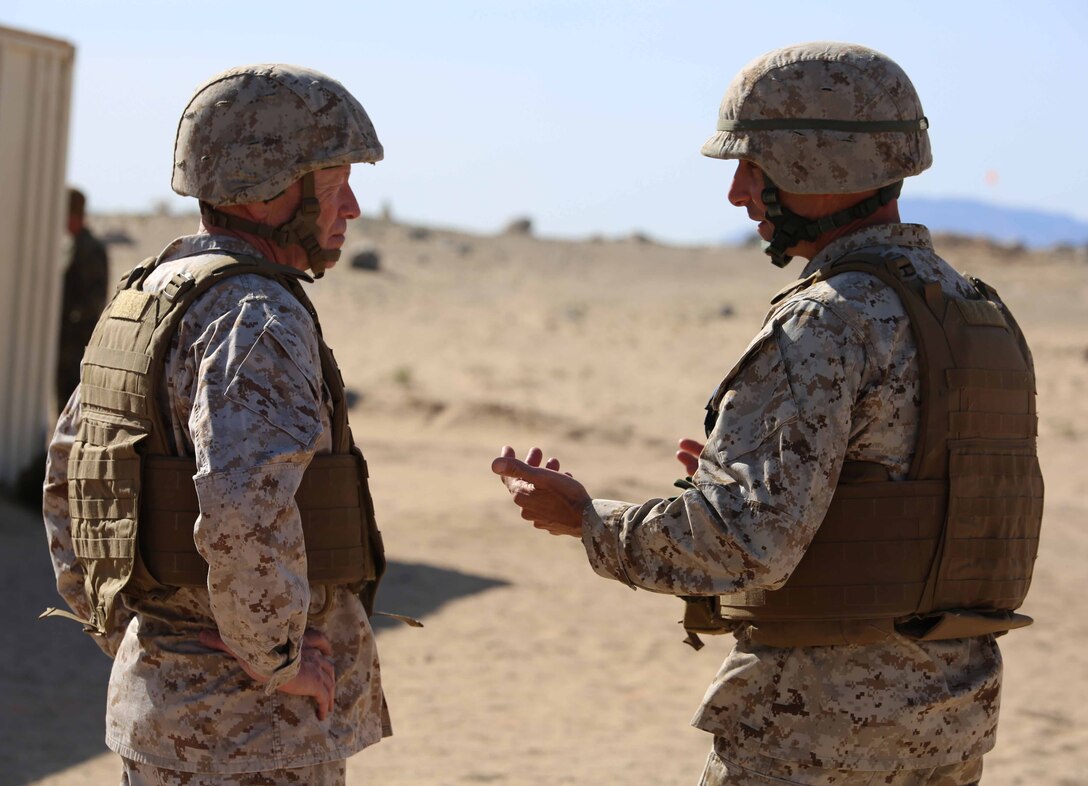Lt. Gen. Kenneth J. Glueck, Jr., left, commanding general, Marine Corps Combat Development Command, speaks with Col. Matthew G. St. Clair, commanding officer, Ground Combat Element Integrated Task Force, during a visit to Range 107, Marine Corps Air Ground Combat Center Twentynine Palms, California, April 8, 2015. From October 2014 to July 2015, the GCEITF will conduct individual and collective level skills training in designated ground combat arms occupational specialties in order to facilitate the standards-based assessment of the physical performance of Marines in a simulated operating environment performing specific ground combat arms tasks. (U.S. Marine Corps photo by Cpl. Paul S. Martinez/Released)